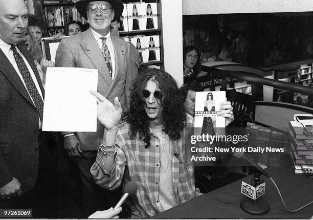 Howard Stern holds his book at an autograph session.