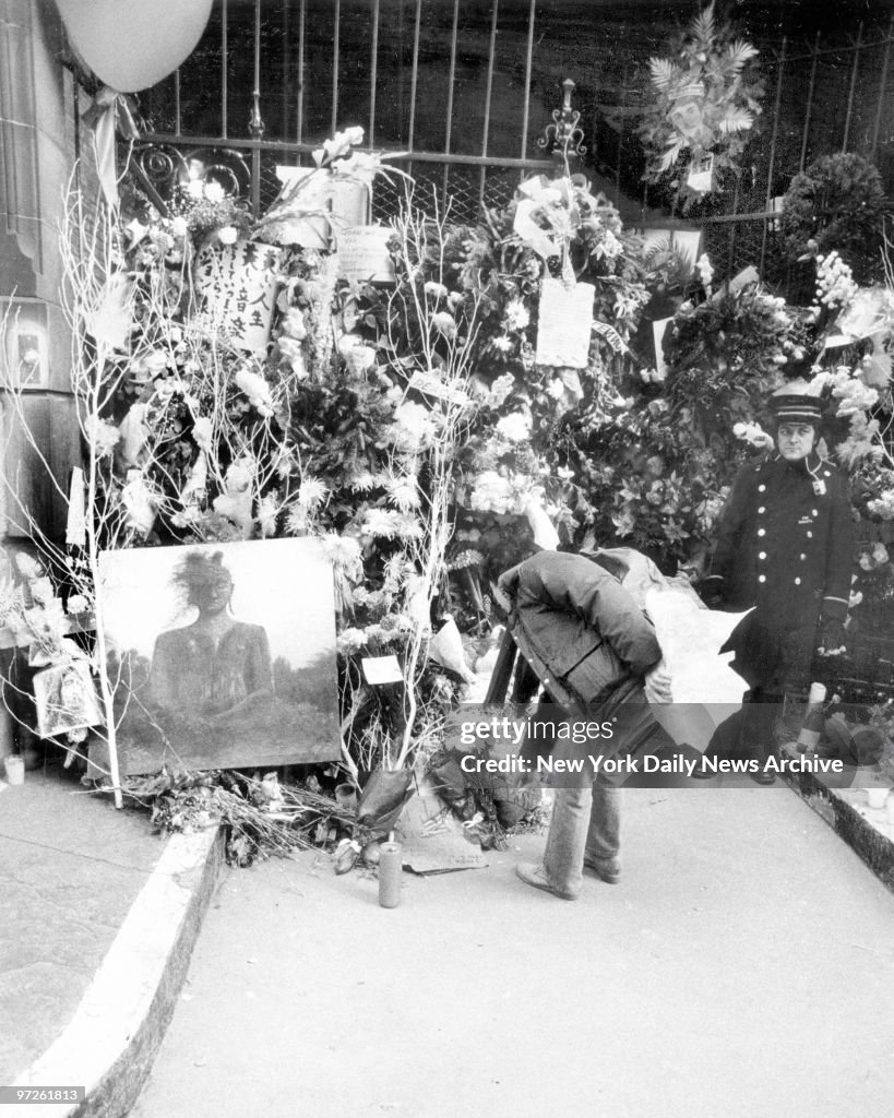 Mourner places bouquet among other items including an oil pa