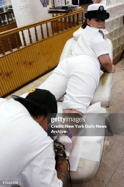 Candice Scott of the USS John F. Kennedy looks over her shoulder to see how her new tattoo is progressing at Kingdom Tattoo in Greenwich Village....