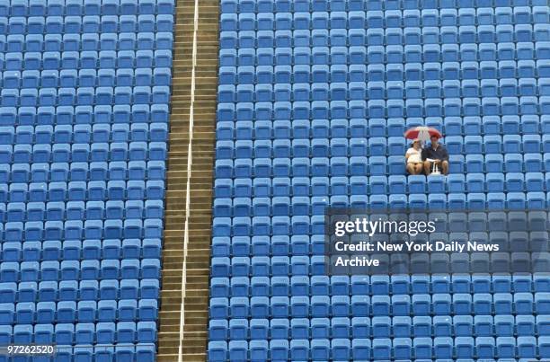 Fans keep a lonely vigil under their umbrella as they wait - and hope - for tennis matches, delayed by torrential rain, to get underway at the U.S....