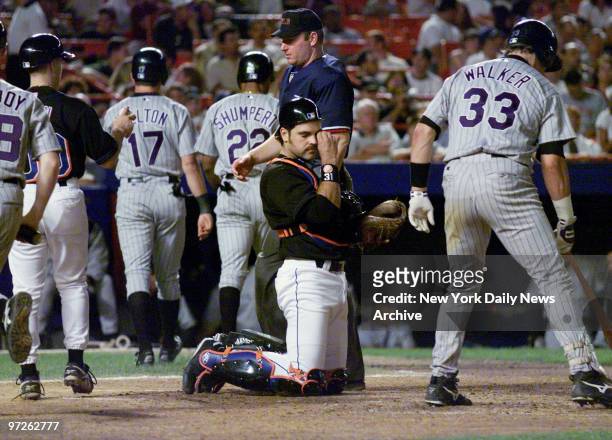 Larry Walker steps to the plate as New York Mets' catcher Mike Piazza wipes his face after Todd Helton and Terry Shumpert scored in the eighth...