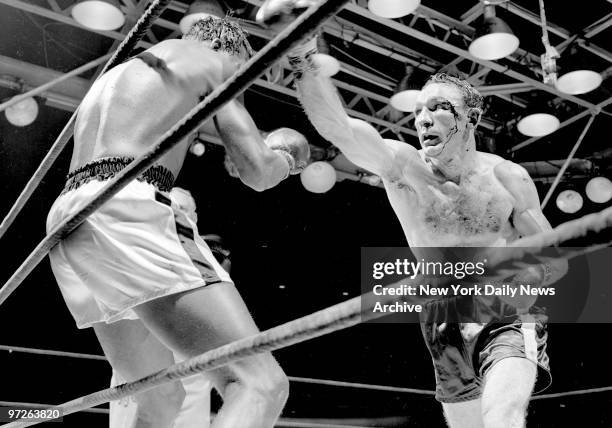 Blood streams from cut near Carmen Basilio's eye as he throws right hand bomb at Sugar Ray Robinson, pinned up against ropes in 11th.