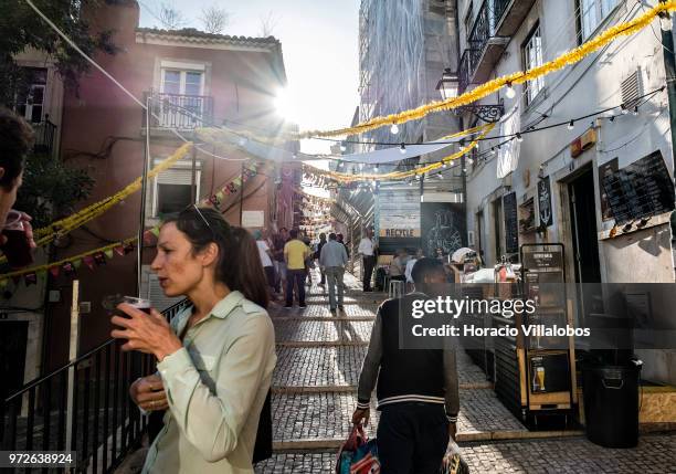 Visitors have a drink in the old quarter of Bica on June 12, 2018 in Lisbon, Portugal. Bica is one of the historic neighborhoods filled up with food...
