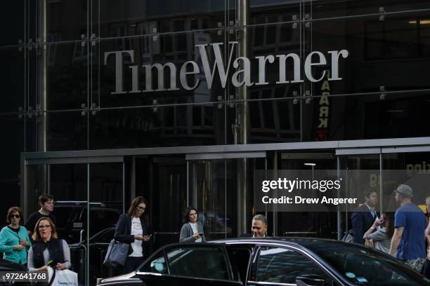 People walk past the Time Warner Center, June 12, 2018 in New York City. A federal judge today said that AT&T can move forward with its $85 billion...