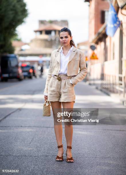 Doina Ciobanu wearing beige shorts, jacket, straw bag is seen during the 94th Pitti Immagine Uomo on June 12, 2018 in Florence, Italy