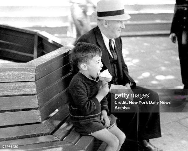 In Palisades Amusement Park feeling the need of some rest, Dad parks himself on a bench while his son goes to work on a giant ice cream cone.