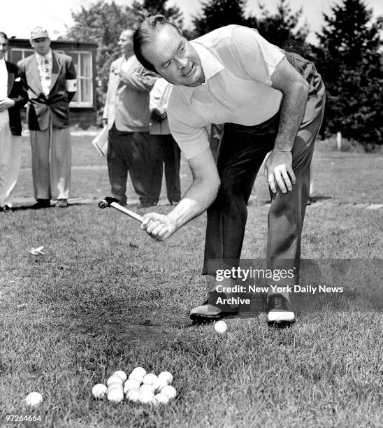 Bob Hope practices before teeing off by using a hammer to drive home his shots at the Meadowbrook Club in Westbury, Long Island.