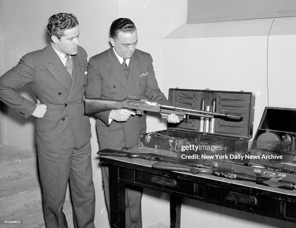 FBI director J. Edgar Hoover looks over weapons.