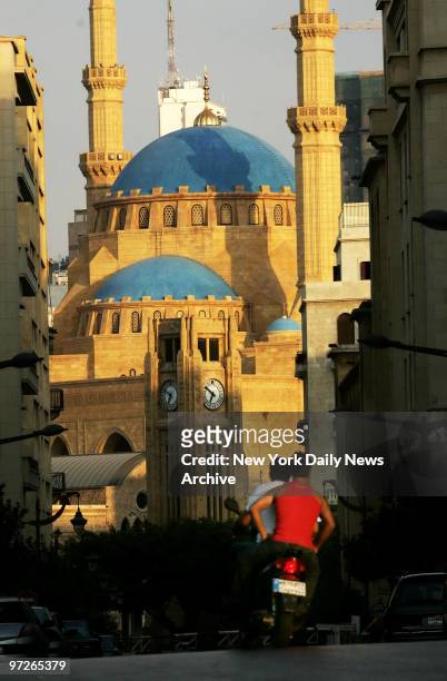 Lebanese men ride a motor bike in front of the Mohammed Al-Amin Mosque in central Beirut, which unlike the devastated southern areas of the city, has...
