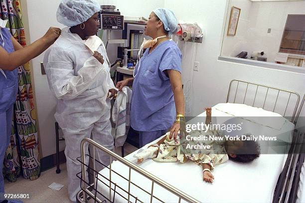 Fela Santos is helped into "scrubs" as she arrives for open-heart surgery on her daughter Merolyn Rosario at Columbia-Presbyterian Babies and...