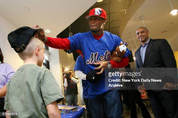 New York Mets' shortstop Jose Reyes puts a Mets cap on a child, as Mets' general manager Omar Minaya looks on, at The Zone, a therapeutic and...