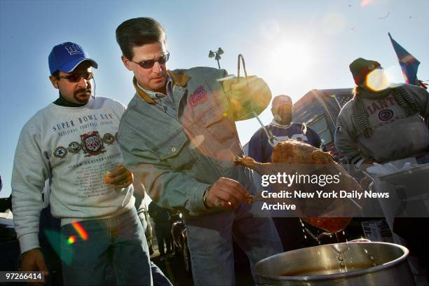 Lenny Vasile of Point Pleasant, N.J., pulls his turkey out of the deep fryer during tailgating festivities before the New York Giants' game against...