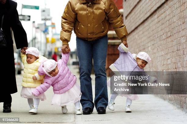 Fifteen-month-old triplets Kaylee, Kylie and Katie Weston waddle down the sidewalk in the hands of mom Sonia Lopez and grandmother Denise Brown after...