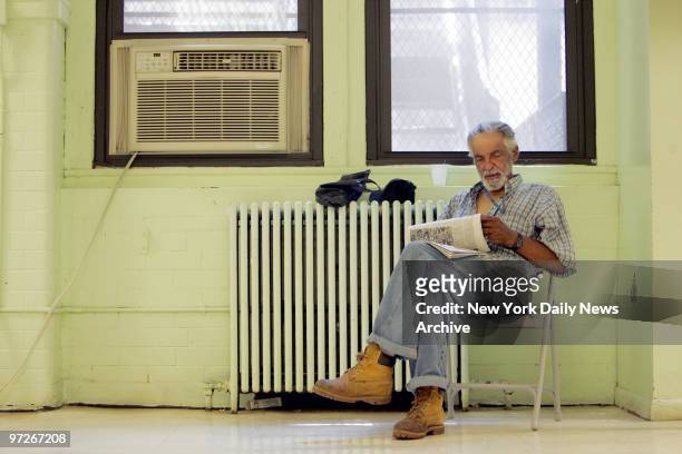 Moises Rios, of East Harlem, finds a nice spot near a large air conditioner to read a paper as he escapes the heat at the Leonard Covello Senior...