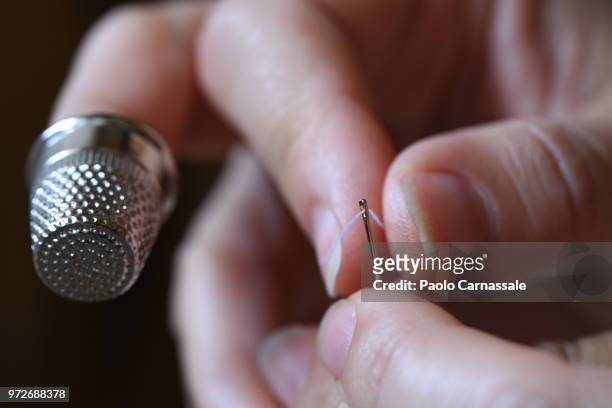close-up of human hand with needle, thimble and thread. - thimble stock pictures, royalty-free photos & images