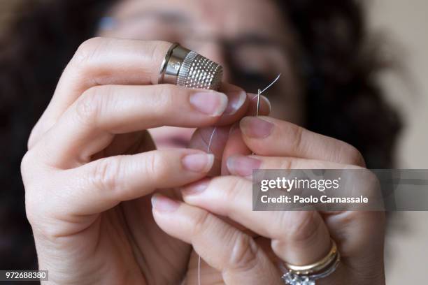 woman with thimble threading sewing needle - mani fili foto e immagini stock