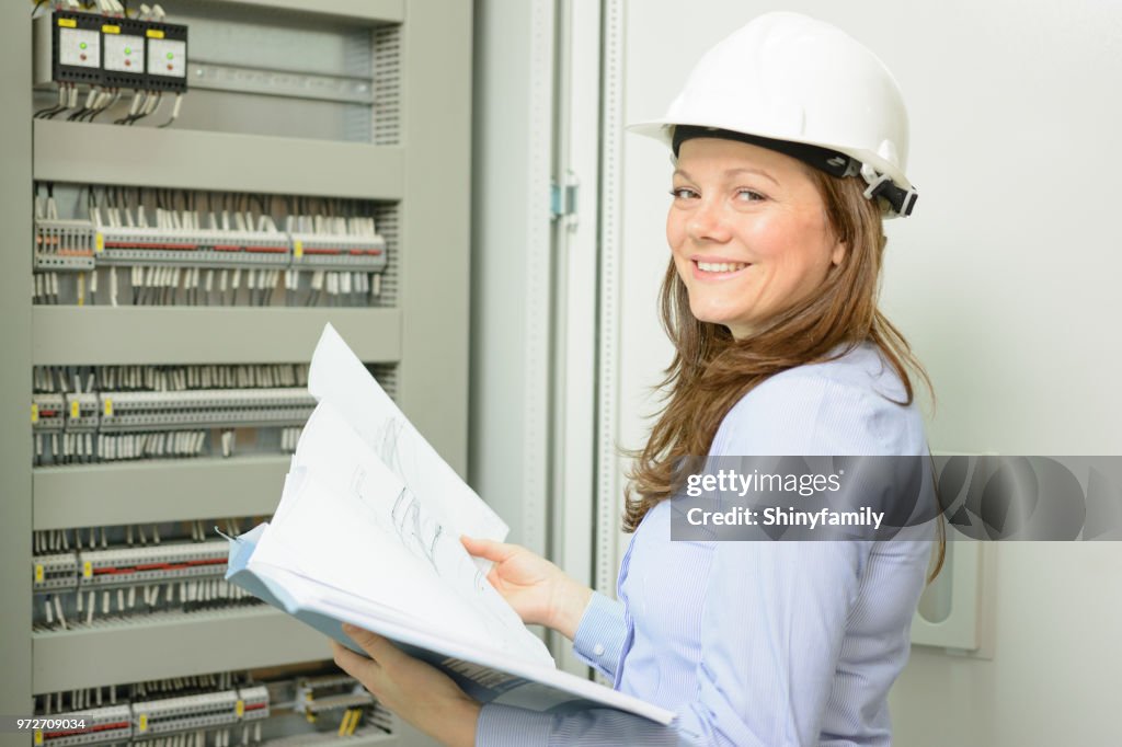 Female engineer looking at blueprints in control room