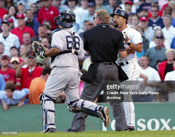 Boston Red Sox's Dave Roberts is held back by home plate umpire Jim Wolf and New York Yankees' catcher Dioner Navarro after he was brushed back by...