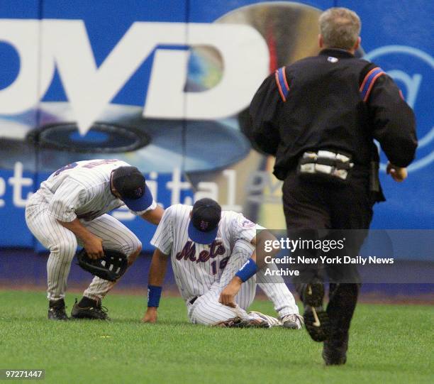 New York Mets' trainer races to attend to outfielder Derek Bell as Jay Payton checks on him. Bell felt light-headed in the fifth inning and was...