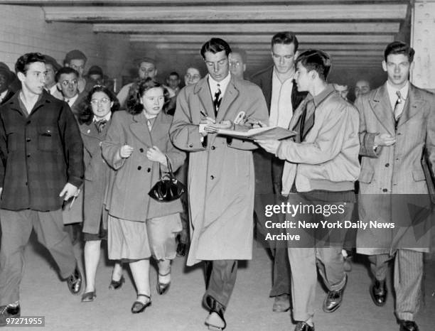 The Yanks ARE IN , Joe DiMaggio signs autographs for fans who met him at Pennsylvania Station when he arrived back in town with the World Champions....