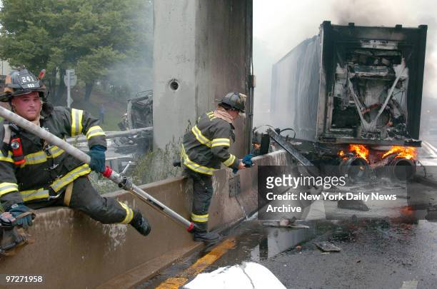 Firefighters climb over a barrier along the Gowanus Expressway to put out flames burning under a truck, which crashed into a concrete pillar under...