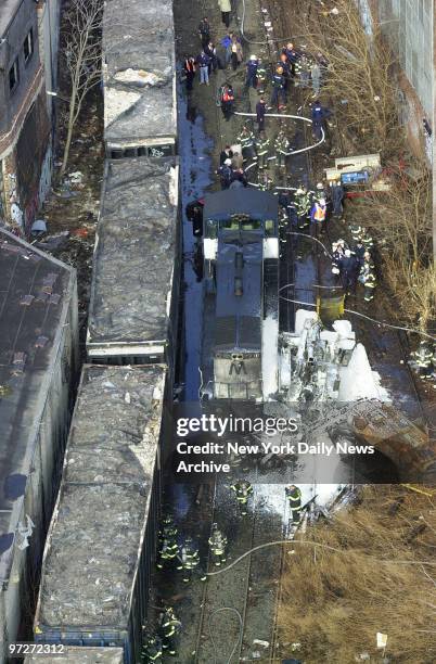 Firefighters gather at the scene of the wreckage after an unmanned locomotive broke loose during a routine switch at the Fresh Pond, Queens, railroad...