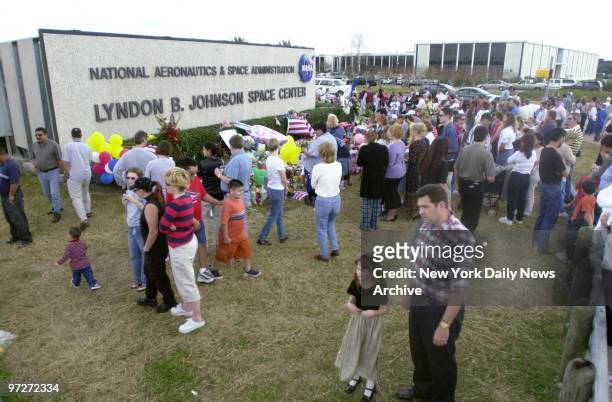 Mourners gather to pray and grieve at a tribute of flowers and flags outside the Johnson Space Center in Houston in memory of the seven astronauts...