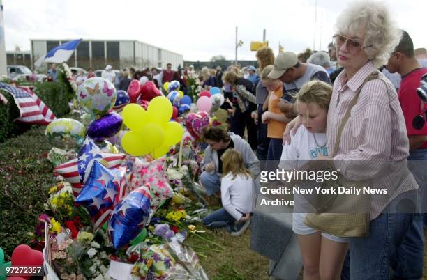Mourners grieve at a tribute of flags and flowers at the Johnson Space Center in Houston to the seven astronauts who died yesterday in the explosion...