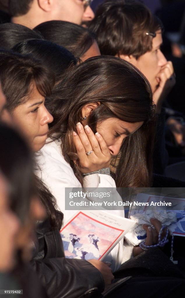 Mourners hold rosary beads and programs as they grieve durin