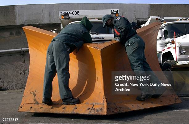 Sanitation Department workers Jose Caraballo and Gregory Hill get the "V" snowplow ready for the expected snow storm at the W. 12th St. And Hudson...
