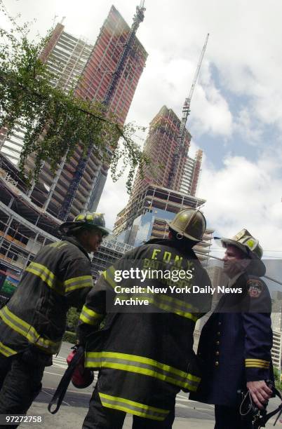 Firefighters look up at the new AOLTime Warner Building going up in Columbus Circle. A construction worker was critically injured and clinging to...