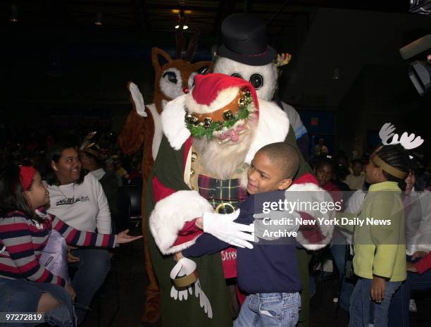 Santa Claus gives a boy a big hug as other kids rush to greet Rudolph the Red-Nosed Reindeer and Frosty the Snowman during the Police Athletic...