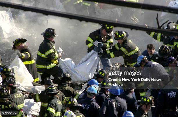 Firefighters remove body of victim from the smoldering remains of American Airlines flight 587 after it crashed in the Rockaway section of Queens.