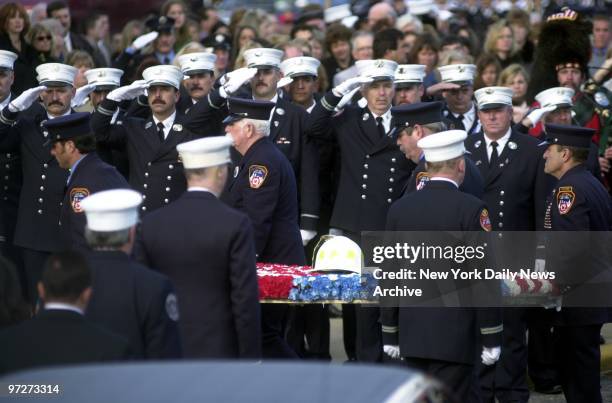 Firefighters salute as fire helmet of Deputy Chief Raymond Downey is carried on a bed of red, white and blue carnations during memorial service at...
