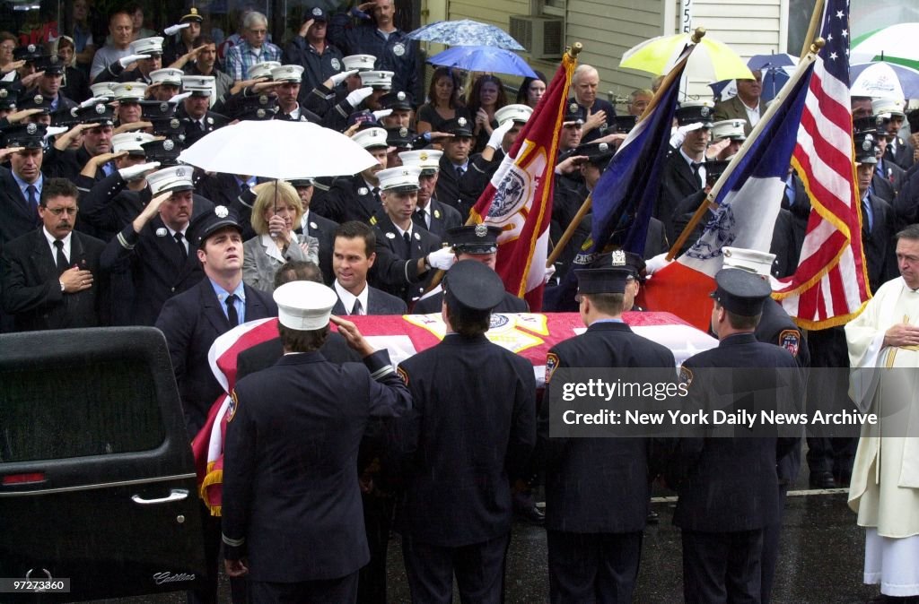Firefighters salute as the coffin of Capt. Martin Egan, a vi