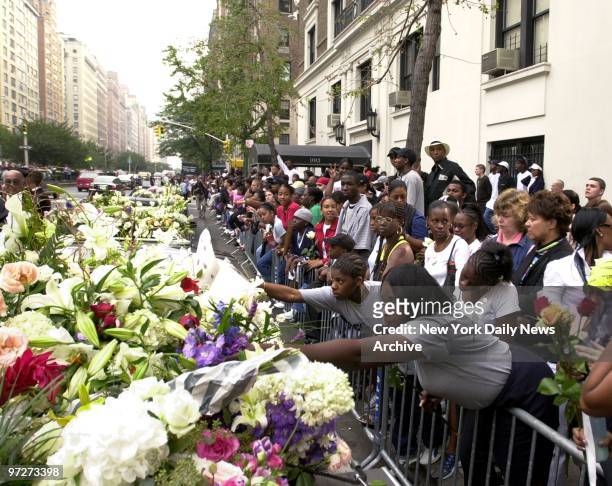 Mourning fans add their tributes to banks of flowers as the casket of R&B star Aaliyah is borne from the Frank E. Campbell Funeral Chapel on 81st St....