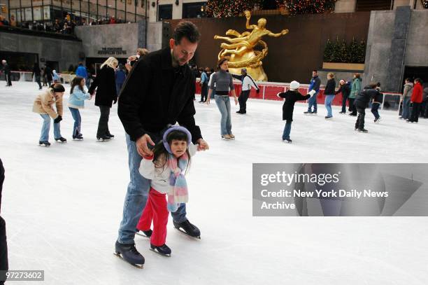 Man takes a little girl for a spin around the Rockefeller Center ice skating rink.