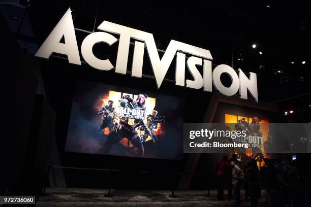 Attendees stand next to signage for Activision Blizzard Inc. Call Of Duty: Black Ops 4 video game during the E3 Electronic Entertainment Expo in Los...