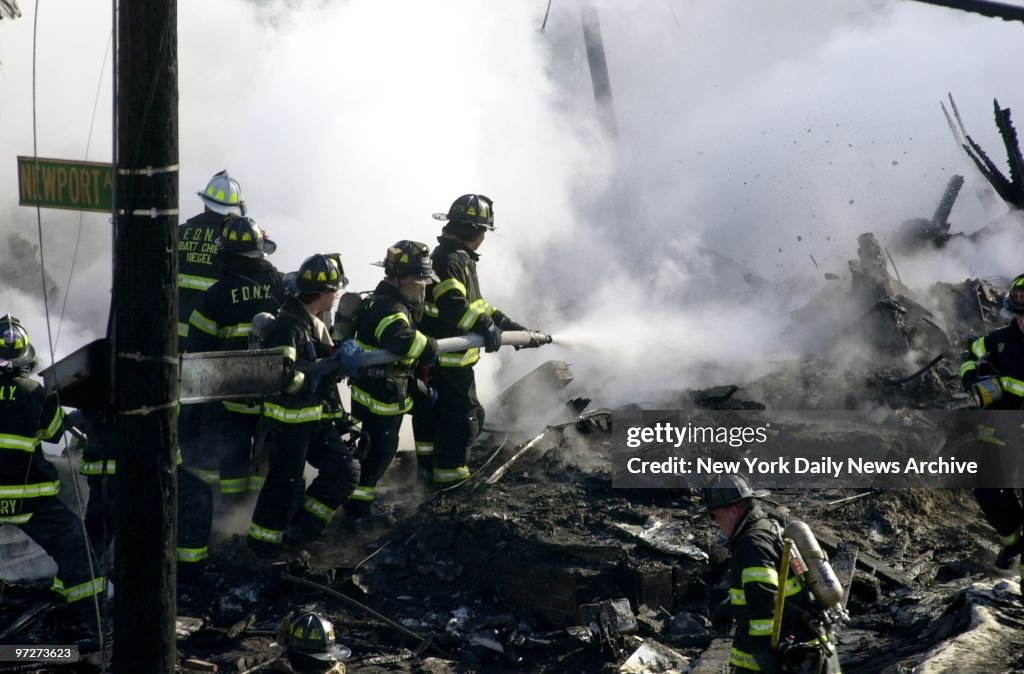 Firefighters spray water on smoldering remains of American A