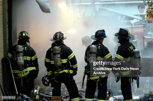 Firefighters stand in the rain at the scene of a fire at the corner of Walton and E. Mount Eden Aves. In the Bronx, where five firefighters were...
