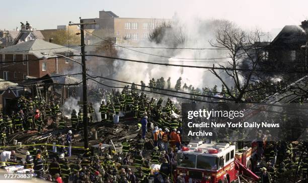 Firefighters try to get fire under control and look for victims in the smoldering remains of American Airlines flight 587 after it crashed in the...