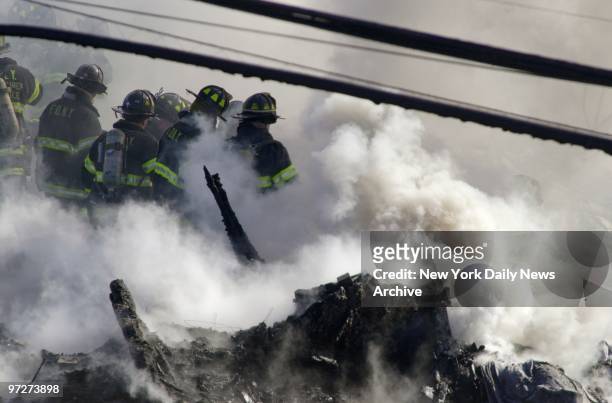 Firefighters try to get fire under control and look for victims in the smoldering remains of American Airlines flight 587 after it crashed in the...