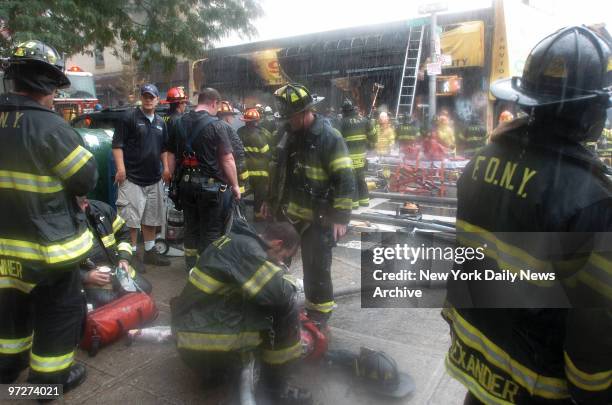 Firefighters wait anxiously in torrential rain outside the scene of a blaze at the Mega 99 Cent store at the corner of Walton Ave. And E. Mount Eden...