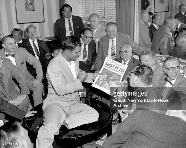 The Daily News' boxing writer Gene Ward shows the champion paper to the champion heavyweight, Rocky Marciano, as they discuss post-fight details.