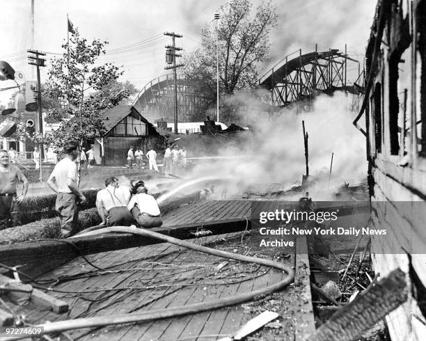Firemen douse boards to keep flames from spreading in Palisades Amusement Park in Fort Lee, N.J. Where fire destroyed property estimated by the...