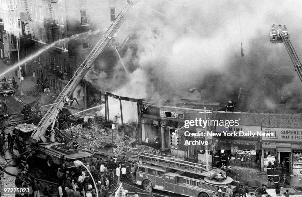 Firemen pour water on a three-alarm fire that erupted about 3pm yesterday in a row of 12 stores at Burnside and Harrison Aves. Five stores burned....