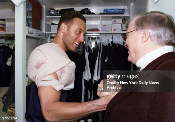 New York Yankees' Derek Jeter, wearing an ice pack on his shoulder, is congratulated in the locker room by principal owner George Steinbrenner after...