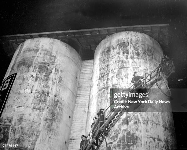 Firemen work hose up stairway to combat blaze in coal silo at 93-08 183d St., Jamaica, Queens. Three alarms were sounded before the fire was brought...