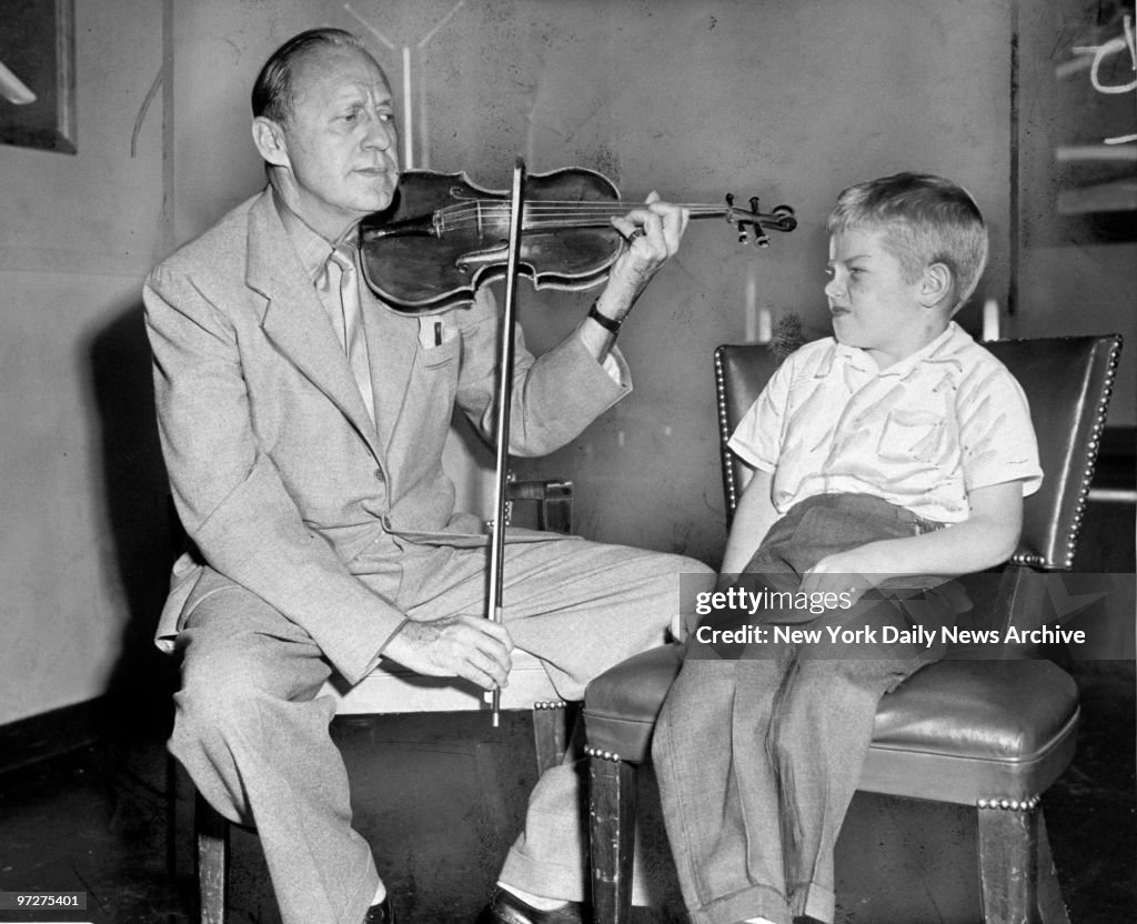 Jack Benny plays his violin for 6-year-old Bruce Milne of Wo