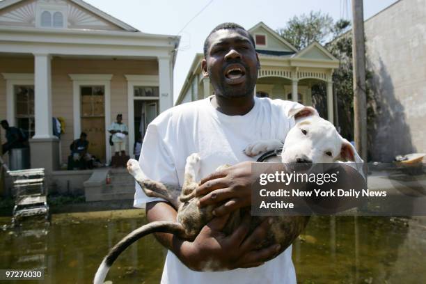 Lonzo Cutler who doesn't want to leave his pit bull behind, cradles the dog in front of his flooded home in the Ninth Ward neighborhood of New...